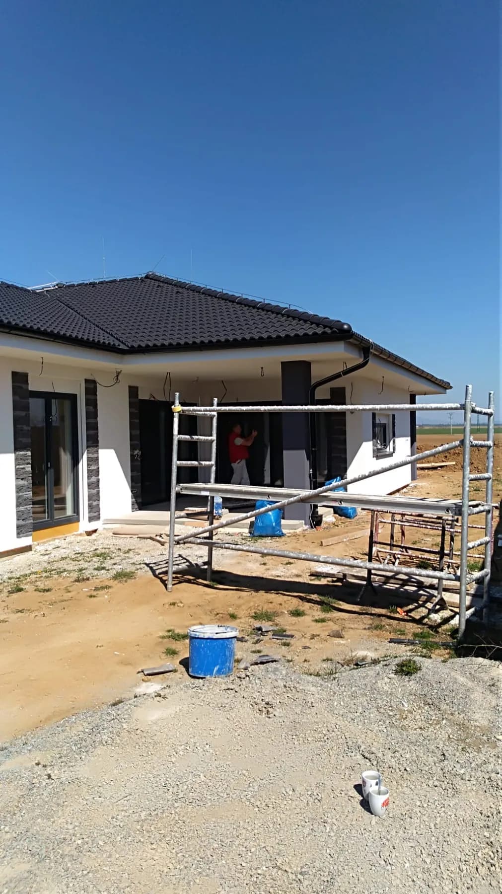 Novostavba bungalovu s rozpracovanou bielou fasádou a lešením