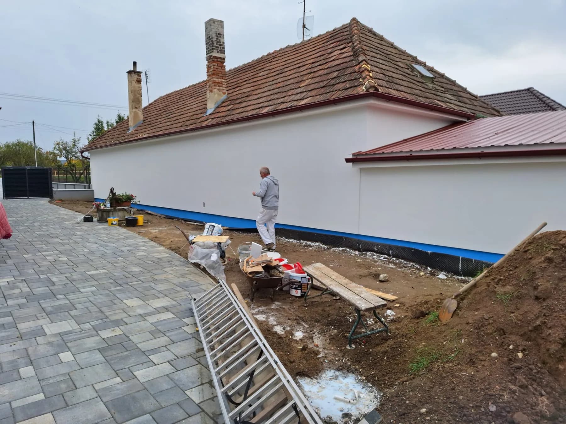 Tá istá hospodárska budova s dokončenou bielou fasádou a novou dlažbou